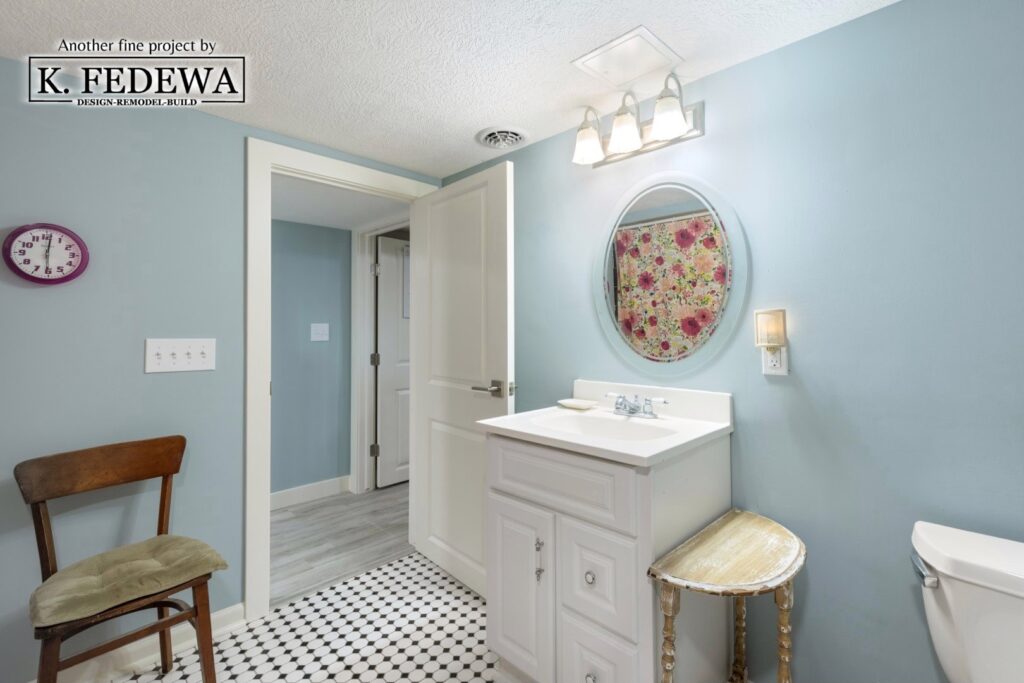 Basement bathroom with light blue walls, a white vanity, and black and white checkered flooring.