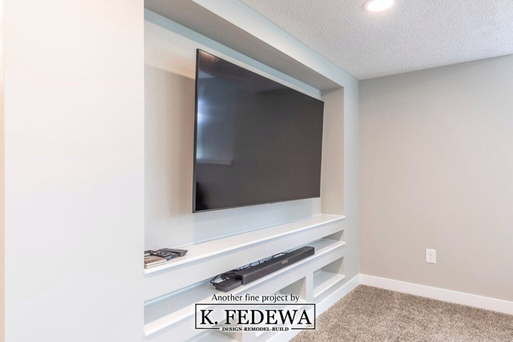 Built-in shelving with LED TV mounted on the wall in a basement remodel.