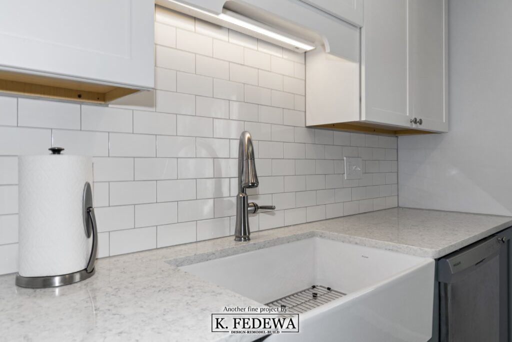 New white farmhouse apron sink inset into a pure white quartz countertop along with a new stainless steel faucet.