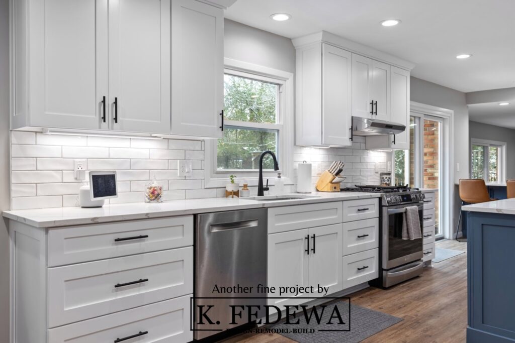 Beautiful white Shaker-style drawers and cabinets with a white subway tile backsplash and stainless-steel appliances.