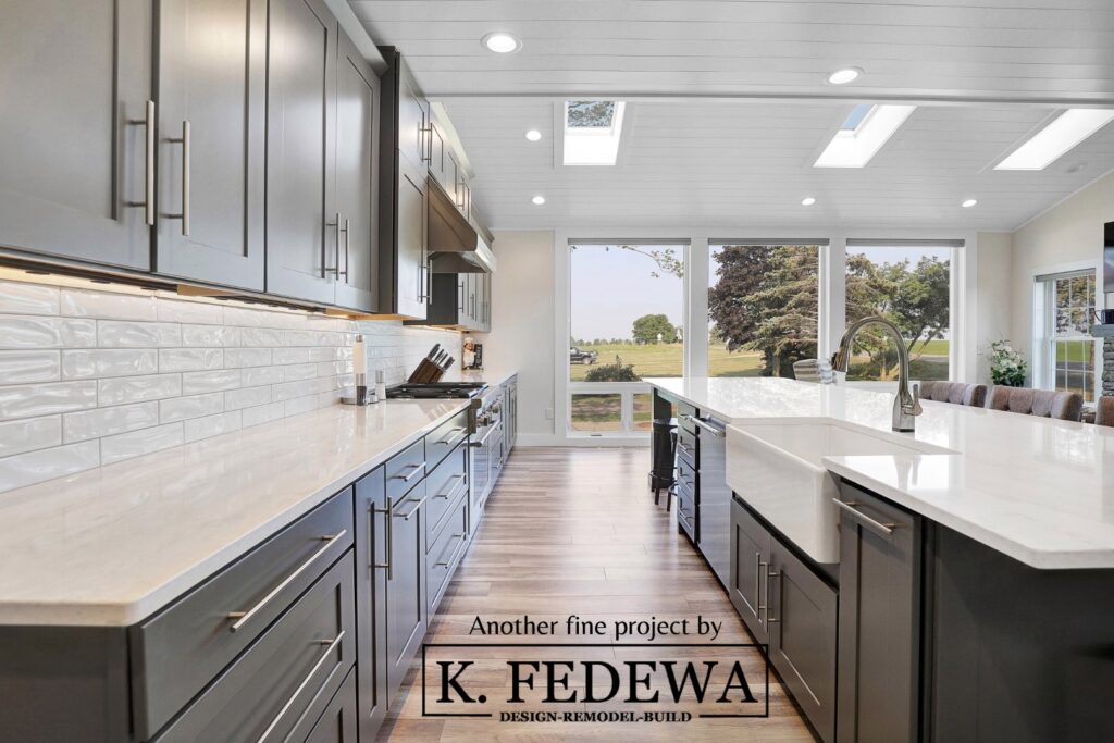 Stunning St. John's, MI kitchen remodel from K. Fedewa Builders with dark cabinets, white countertops, and massive windows and skylights letting in sunlight.