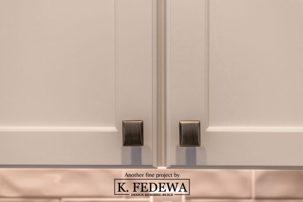 Close-up of square nickel metal cabinets pulls on white cabinets.
