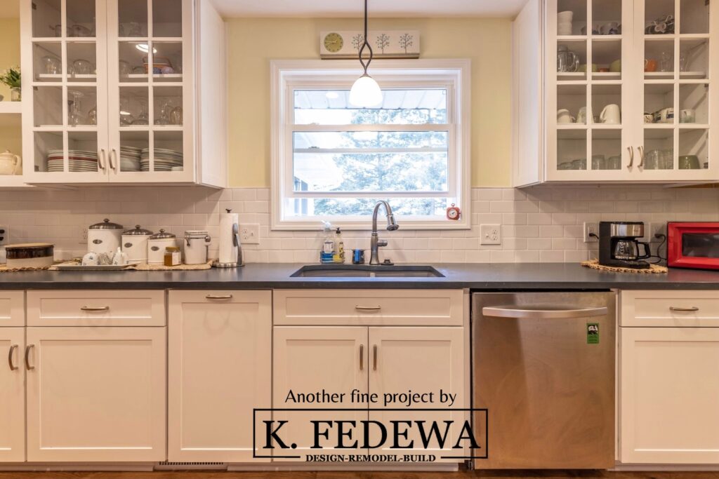 Kitchen remodel by K. Fedewa Builders with white cabinets on the bottom and white and clear glass cabinets on the top.