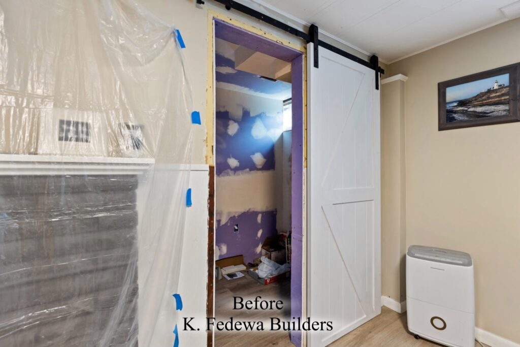 Photo showing DIY remodel of bathroom with barn-style door looking in from bedroom.