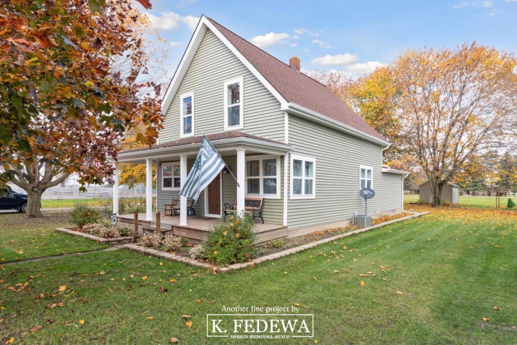 Beautifully resided home in East Lansing with new green siding and trees with Fall-colored leaves.