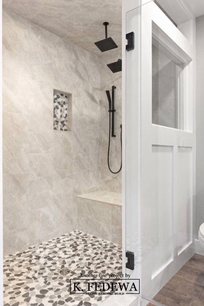 Beautiful, giant walk-in shower with river-rock flooring and white wall frame.